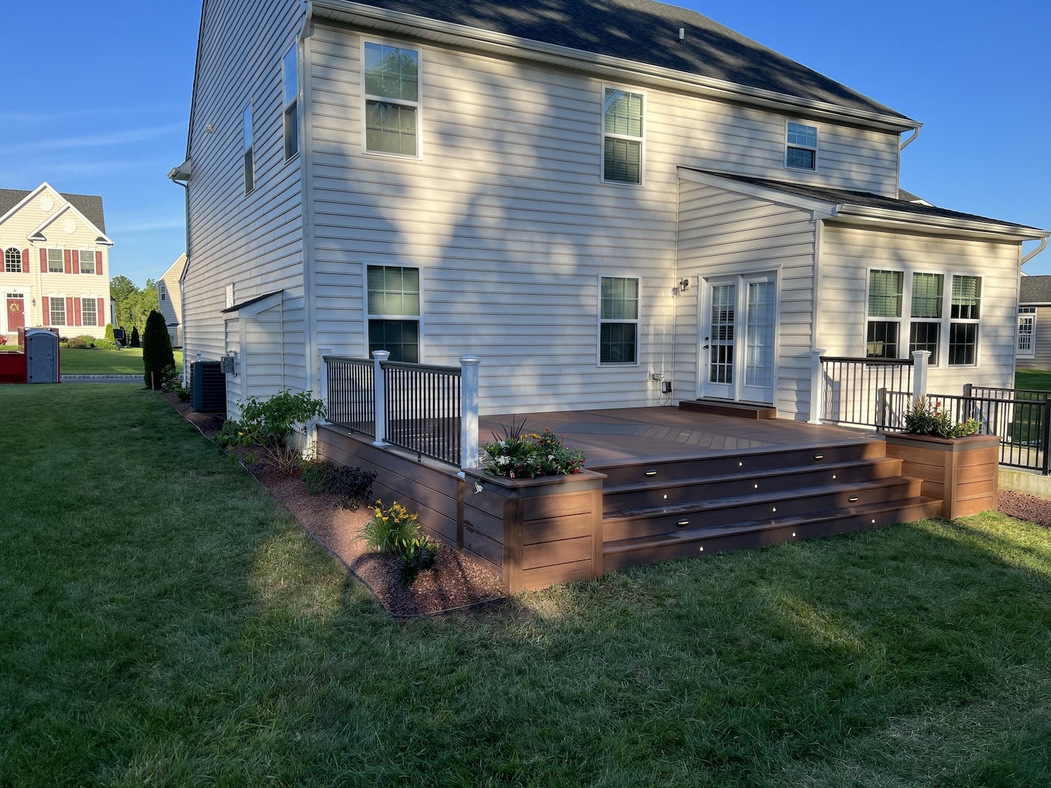 Back of a home's wooden deck with custom lighting design on the stairs