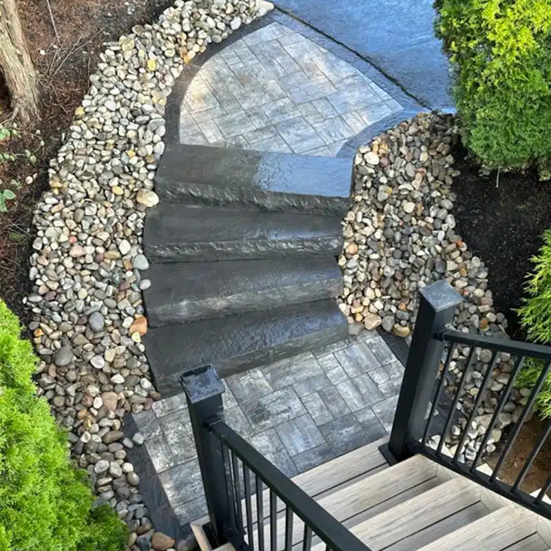 stone hardscaping with brick portions leading to stone stairs and black railing handles